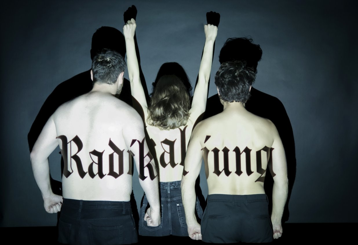 Drei Personen stehen mit nacktem R&uuml;cken zur Kamera, eine rei&szlig;t die Arme nach oben und auf ihrer Haut steht der Schriftzug &quot;Radikal jung&quot;. | © Sarah Kralisch