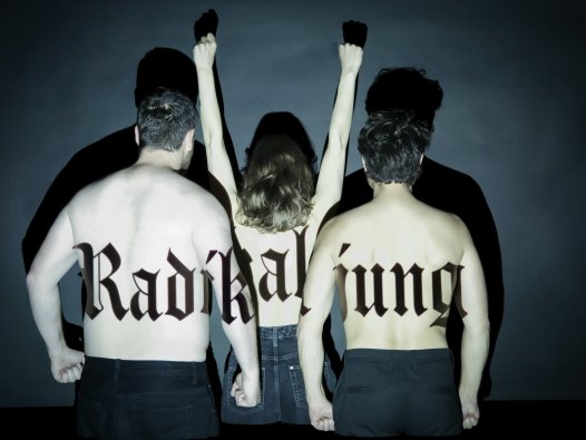 Drei Personen stehen mit nacktem Rücken zur Kamera, eine reißt die Arme nach oben und auf ihrer Haut steht der Schriftzug "Radikal jung". | © Sarah Kralisch